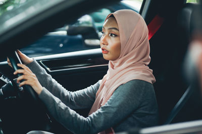 Side view of young woman sitting in car