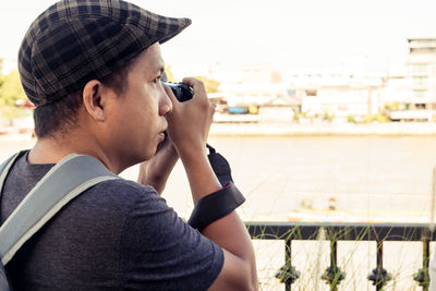 Close-up of man photographing against river in city