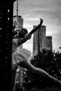 Low angle view woman dancing against building and sky