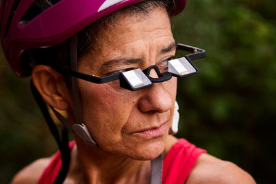 Closeup of active senior female climber looking away while wearing prism glasses during hiking