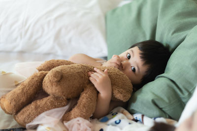 Portrait of cute baby girl resting on bed at home