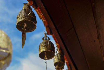 Low angle view of illuminated lamp hanging by building against sky