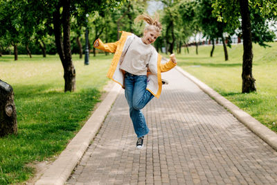 A teenage girl walking in the park jumping with ice cream in her hands. child outdoors