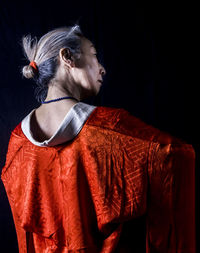 Rear view of woman standing against black background