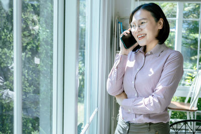 Young woman looking through window