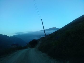 Road amidst mountains against clear blue sky