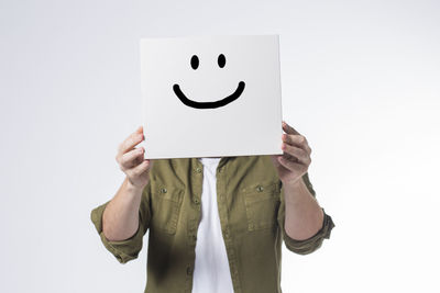 Midsection of person holding paper against white background