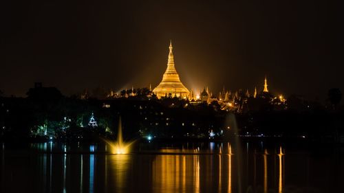 Illuminated pagoda against clear sky with waterfront