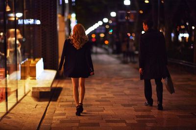 Rear view of business people walking on sidewalk at night