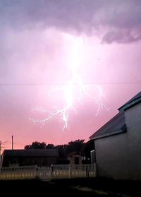 Low angle view of lightning over buildings against sky
