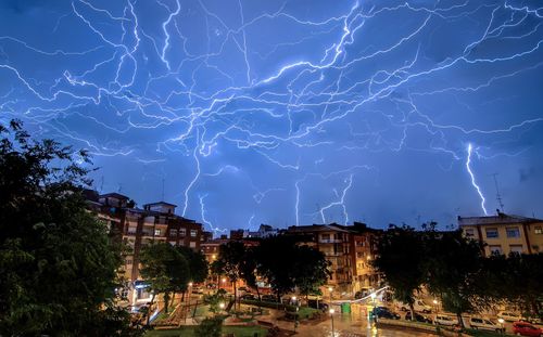 Lightning over illuminated buildings in city at night