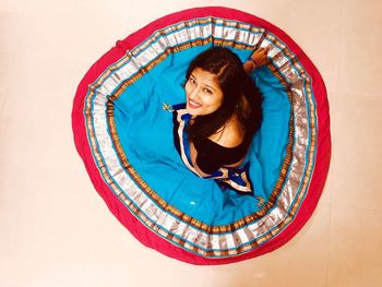 High angle portrait of young woman wearing traditional clothing sitting on floor