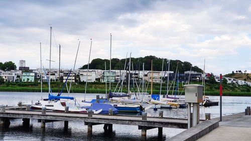 Boats moored at harbor against sky