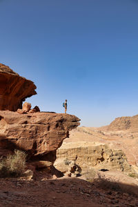 Tourist standing on rock formation in petra archaeological site, jordan