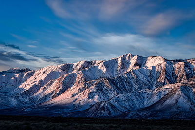 Early morning blue sky with white clouds above snowy eastern sierra nevada mountains