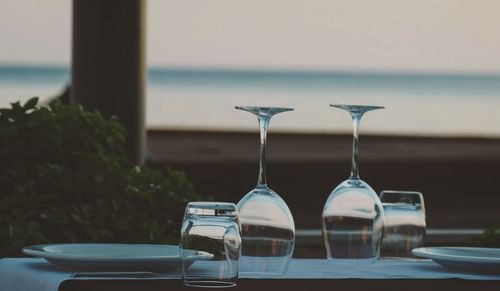 Close-up of glasses on table against sea