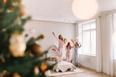 A group of cheerful female friends dance rejoice have fun in the christmas holidays in the bedroom