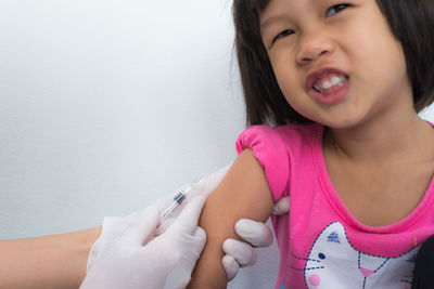 Cropped hands of doctor injecting girl at hospital