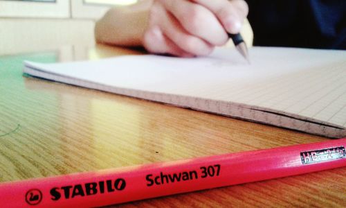 Close-up of hand holding book with text on table