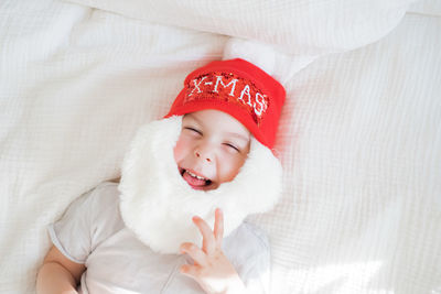 Toddler boy in santa claus costume with beard and red hat on white background