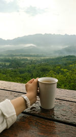 Woman with coffee and mountains against sky