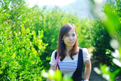 Woman looking away while standing amidst plants in farm