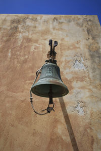 An old bell hanging on the wall of an orthodox church on the island of spinalonga.