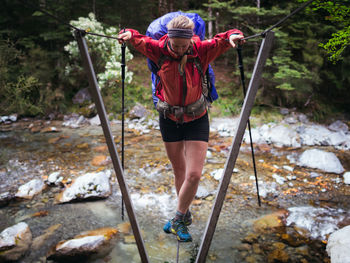 Woman standing on railing on water in forest