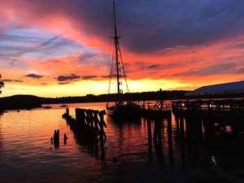 Silhouette boats moored at harbor against sky during sunset