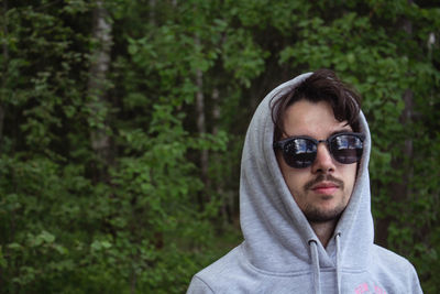 Hooded young man wearing sunglasses in forest