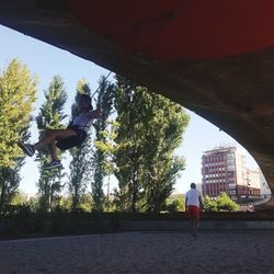 Men jumping in city against sky