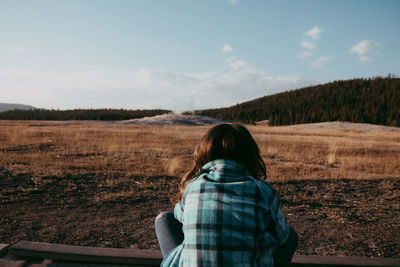 Rear view of girl on field against sky