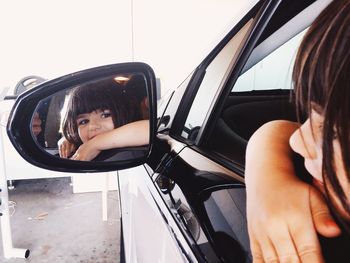 Smiling girl reflecting on side-view mirror