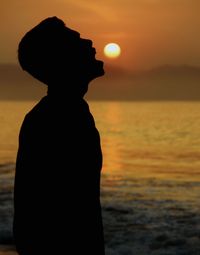 Optical illusion of man eating sun at beach during sunset