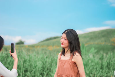 Portrait of beautiful woman using mobile phone against sky