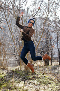 Full length of cheerful woman jumping in forest