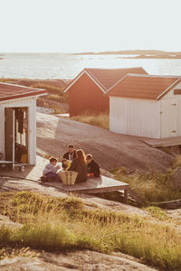 High angle view of family with children sitting outside cabin during sunny day