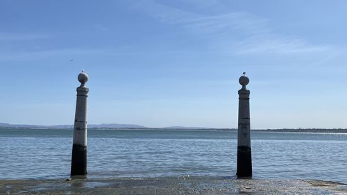 Wooden post in sea against sky
