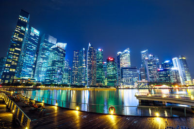 Illuminated buildings by city against sky at night