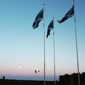 Low angle view of flags against clear sky