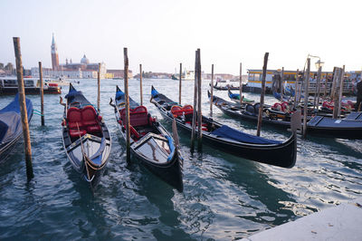 Gondolas moored by wooden post on grand canal against clear sky