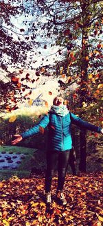 Rear view of woman standing on leaves during autumn