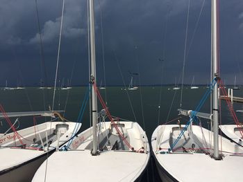 Sailboats moored on sea against sky