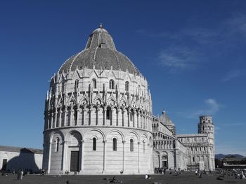 People at leaning tower of pisa against blue sky