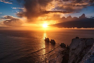 Scenic view of sea against dramatic sky during sunset