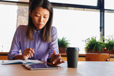 Businesswoman using digital tablet in cafeteria