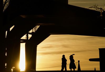 Silhouette people standing against sky during sunset