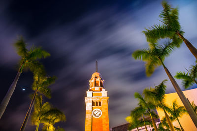 Low angle view of clock tower amidst trees against sky