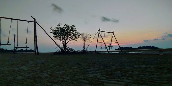 Silhouette trees on field against sky during sunset