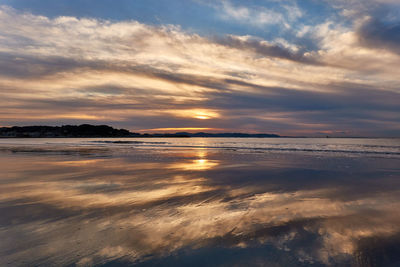 Scenic view of beach against sky during sunrise